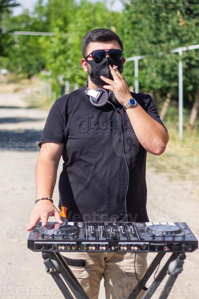 dj com fones de ouvido e misturador dentro a parque, a dj às trabalhos foto