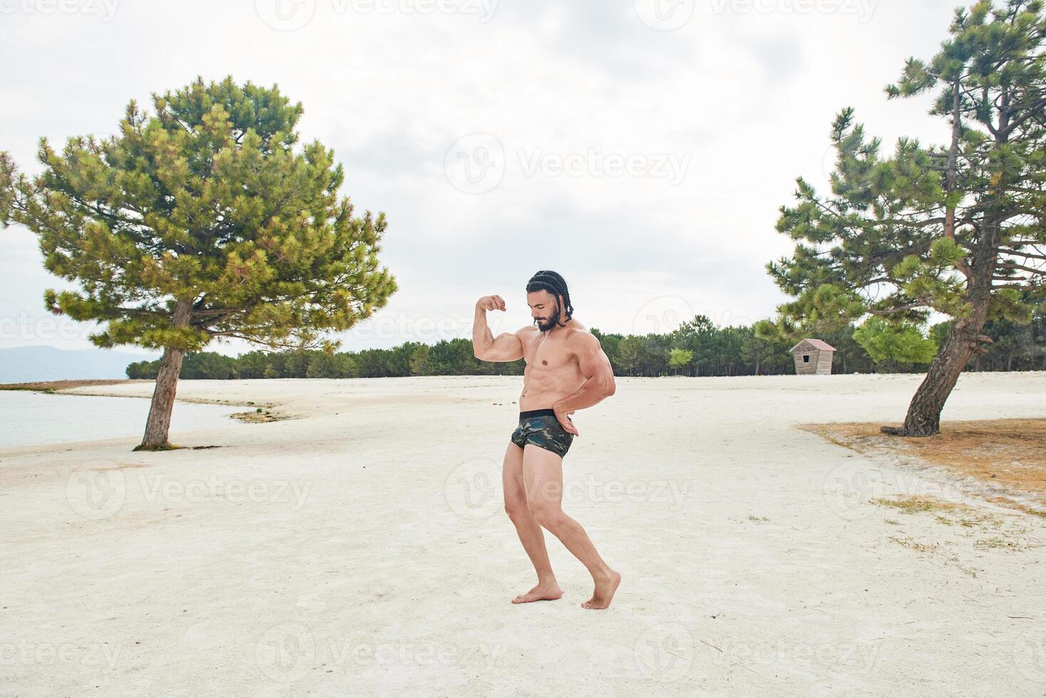 jovem muscular homem exercício em a praia, jovem muscular homem fazendo musculação exercícios em a praia, Atlético jovem homem em a de praia foto