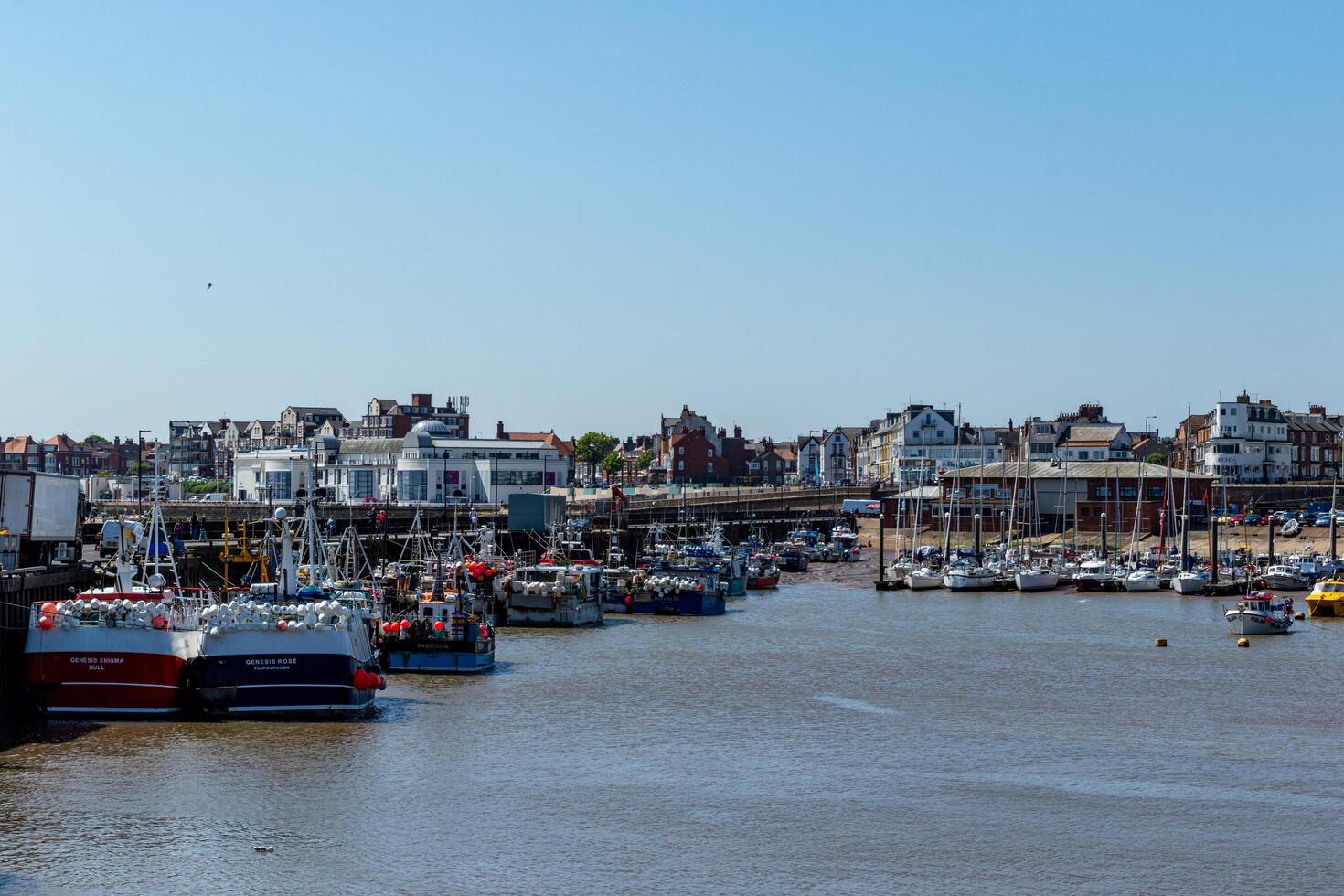 cênico Visão do uma movimentado Porto com barcos e beira-mar edifícios debaixo uma Claro azul céu dentro bridlington, Inglaterra. foto