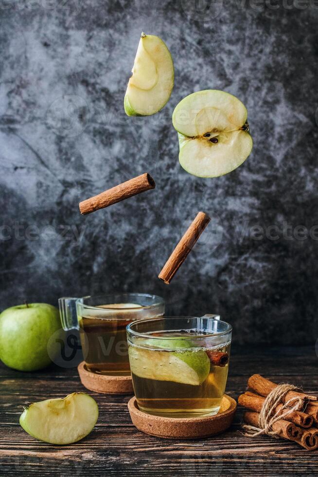 maçã cidra beber com canela e fresco maçãs em Sombrio de madeira fundo. foto