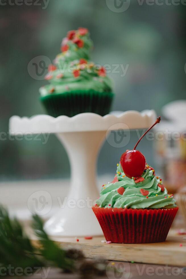 Natal bolos de copo com verde creme geada e vermelho cereja em topo foto