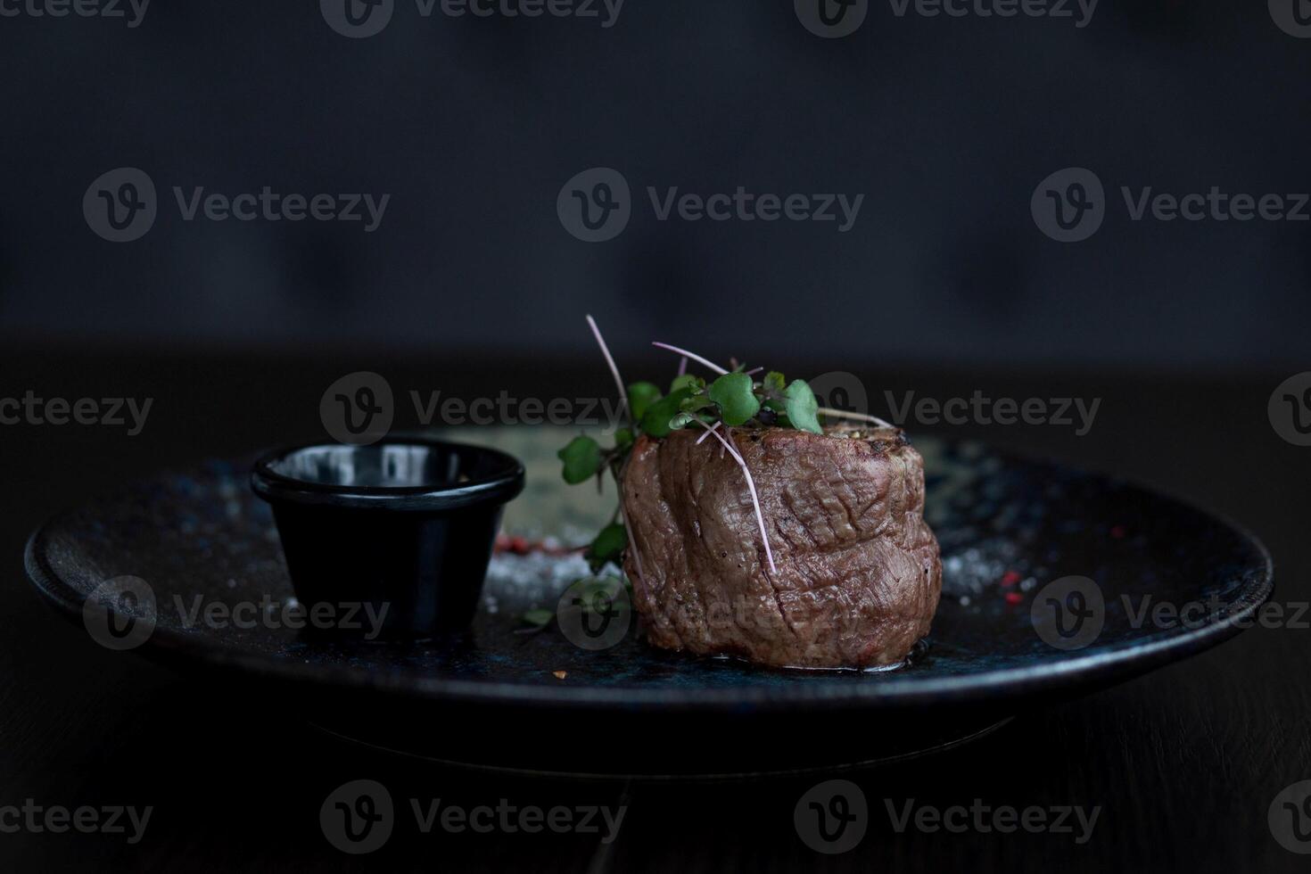 carne bife em uma Preto prato com molho em uma Sombrio fundo foto