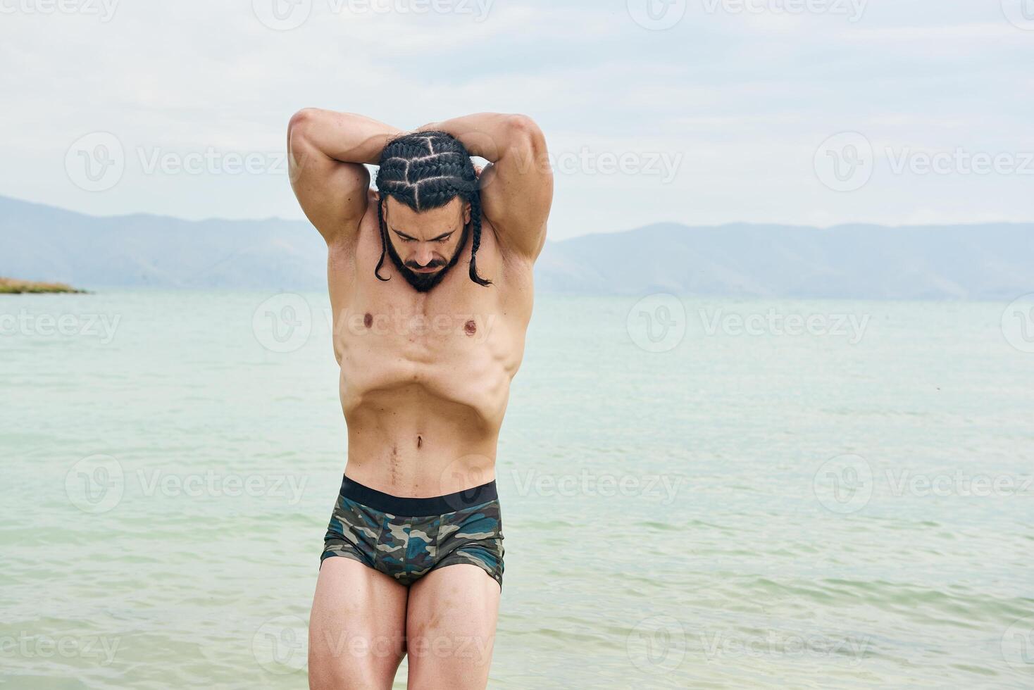 jovem muscular homem exercício em a praia, jovem muscular homem fazendo musculação exercícios em a praia, Atlético jovem homem em a de praia foto