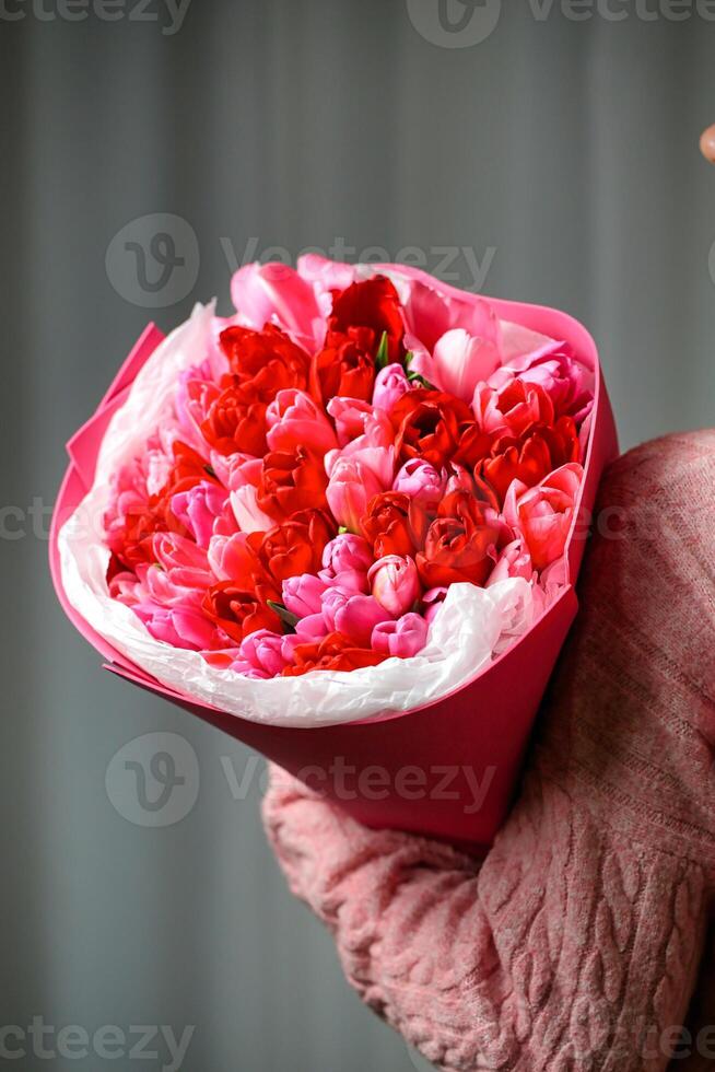 pessoa segurando ramalhete do vermelho e Rosa flores - comovente gesto foto