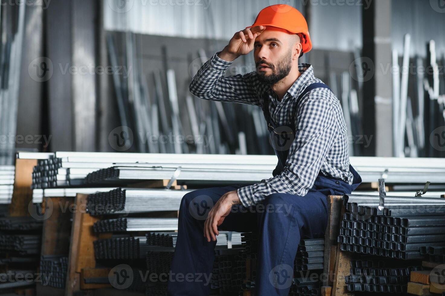 retrato do profissional pesado indústria engenheiro trabalhador vestindo segurança uniforme, Difícil chapéu sorridente. dentro a fundo desfocado ampla industrial fábrica. foto