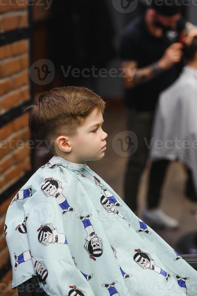 alegre caucasiano Garoto obtendo Penteado dentro barbearia foto