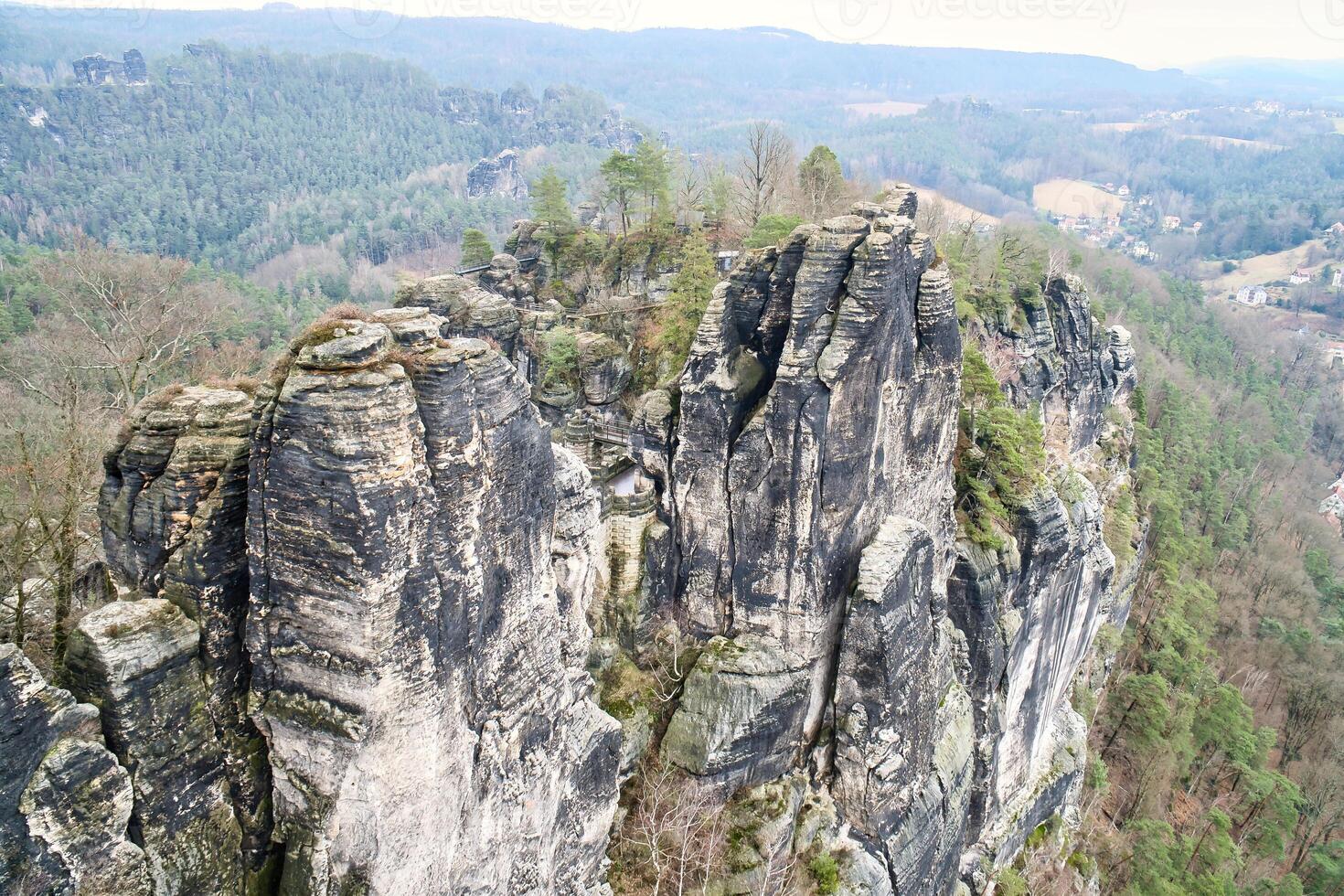 irregular pedras às a Basteibridge. Largo Visão sobre árvores e montanhas. dramático céu foto