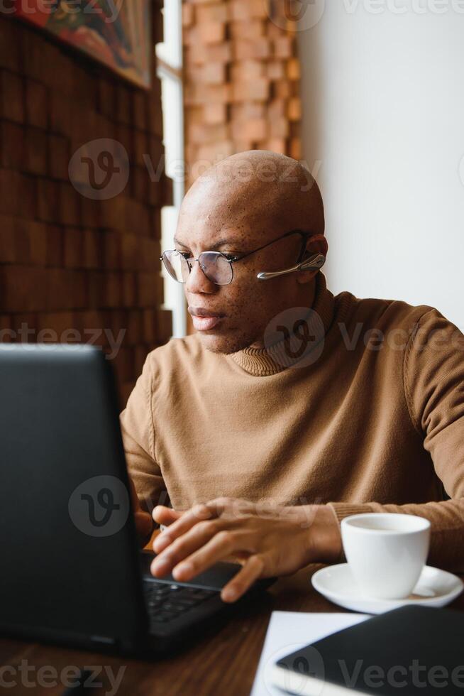 focado africano homem vestindo fones de ouvido assistindo webinar Treinamento fazer notas estude conectados Aprendendo língua em computador, Preto masculino aluna olhando às computador portátil elearning dentro Internet escrever Informação. foto