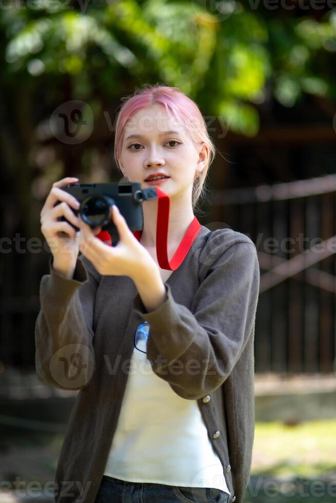 lindo jovem artista mulher levando foto dentro flores jardim. jovem fofa menina levar a Câmera dentro a jardim