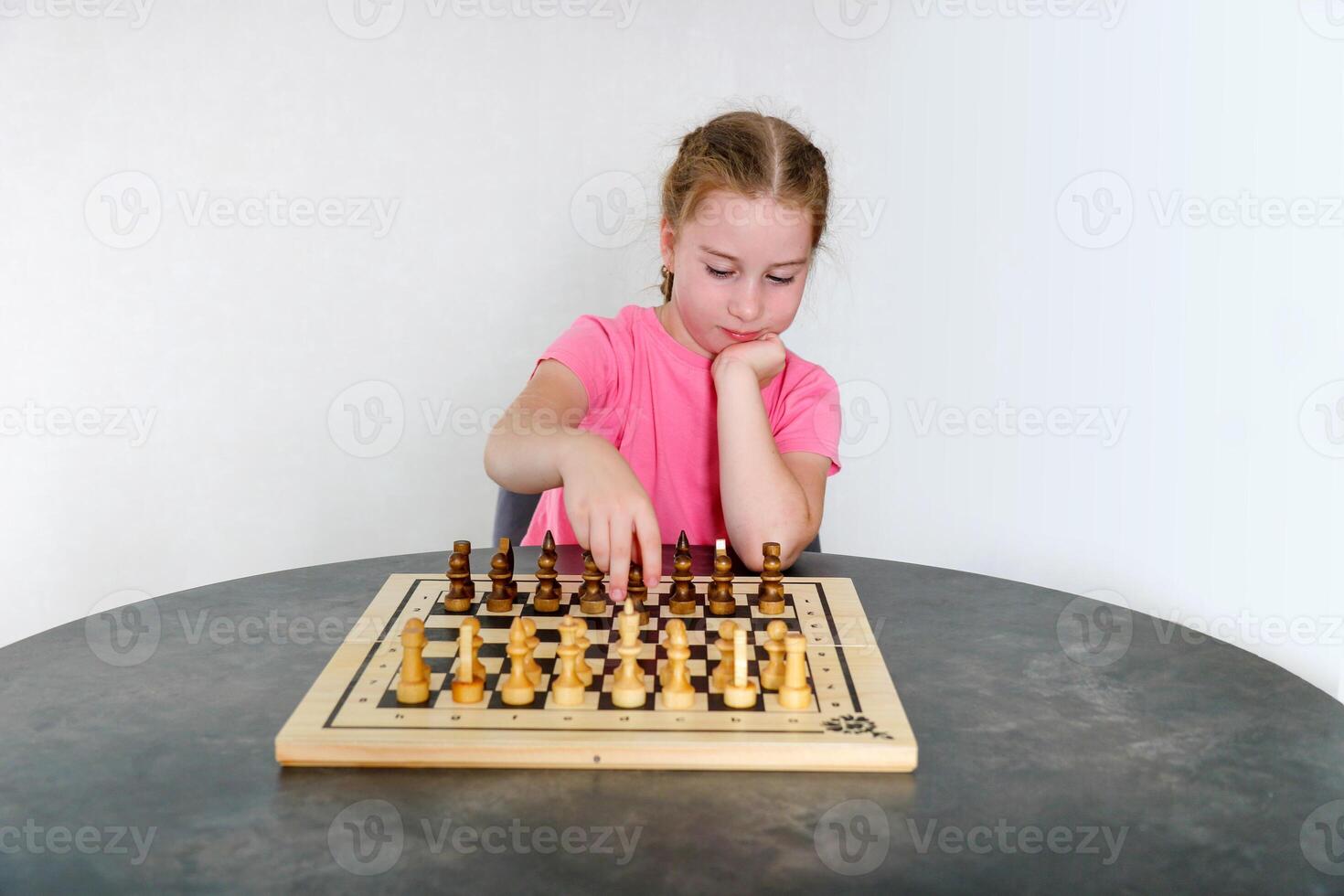 menina faz movimentos com peças em a tabuleiro de xadrez foto