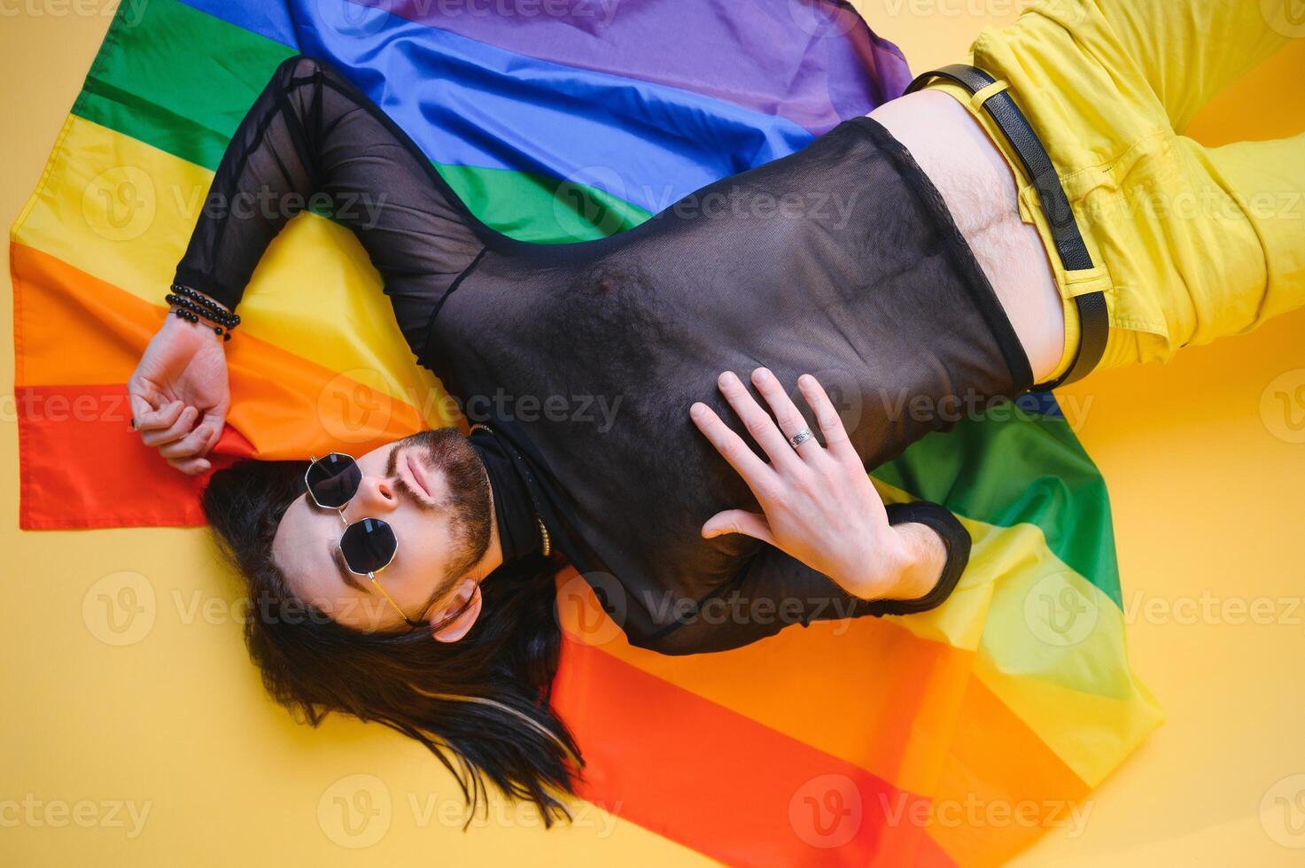 gay homem com uma gay orgulho bandeira sorridente e olhando longe em amarelo fundo foto