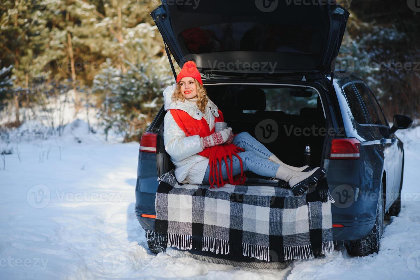 jovem mulher sentado dentro carro tronco bebendo caloroso chá e leva uma selfie às inverno nevou dia. foto