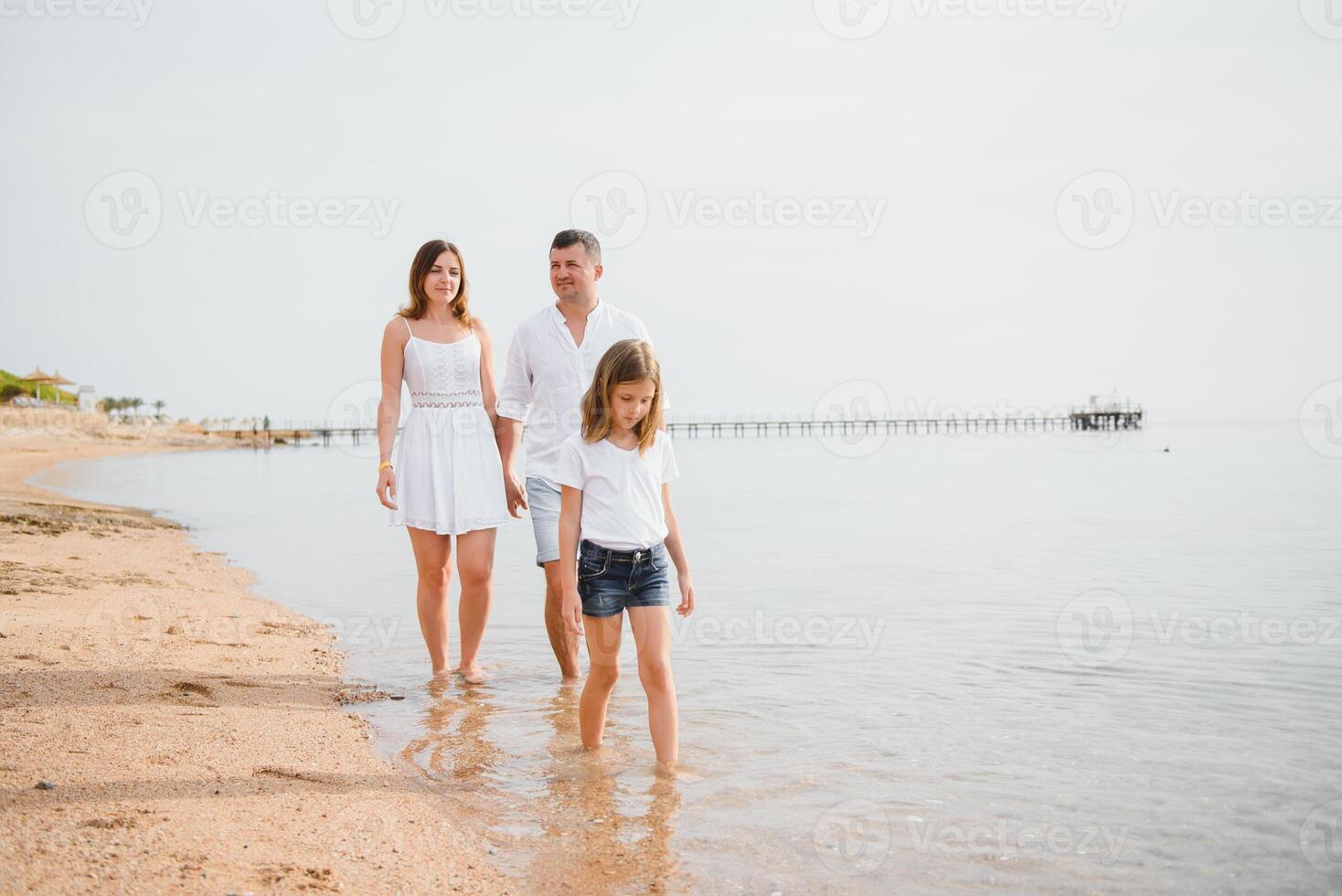 família feliz caminhando na praia foto