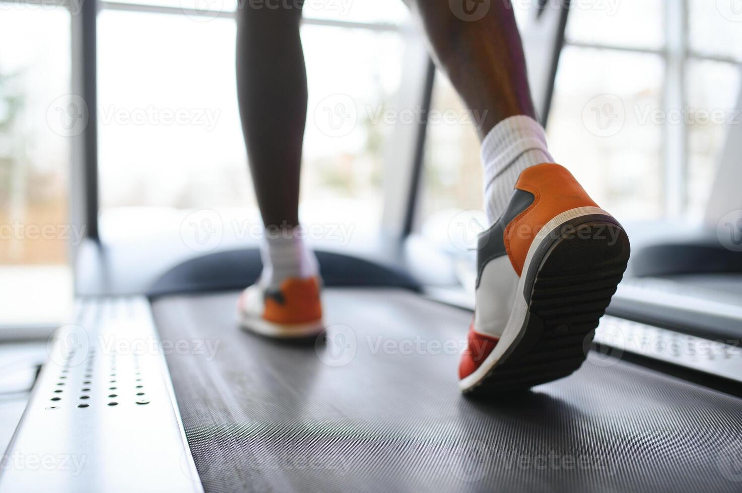 costas Visão do irreconhecível masculino pernas corrida em esteira dentro academia. foto