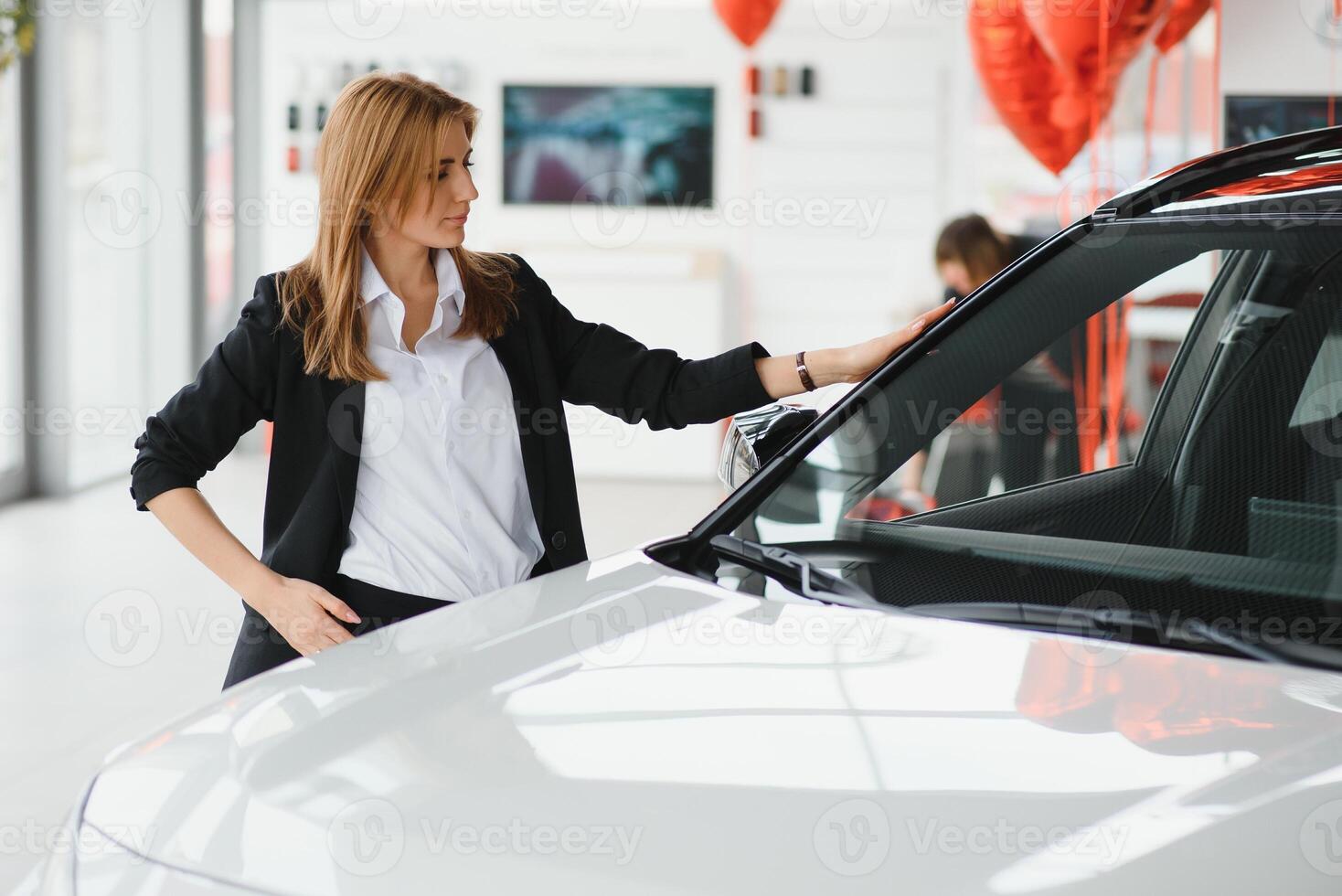 jovem lindo mulher mostrando dela amor para uma carro dentro uma carro showroom. foto