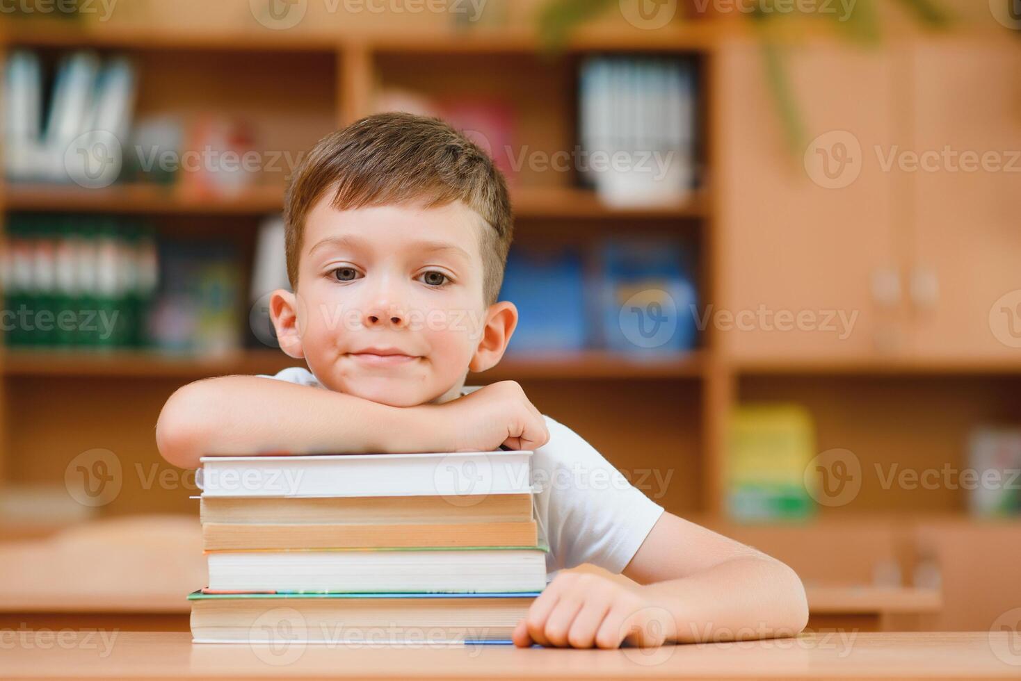 Educação e escola conceito - sorridente pequeno Garoto com muitos livros às escola foto