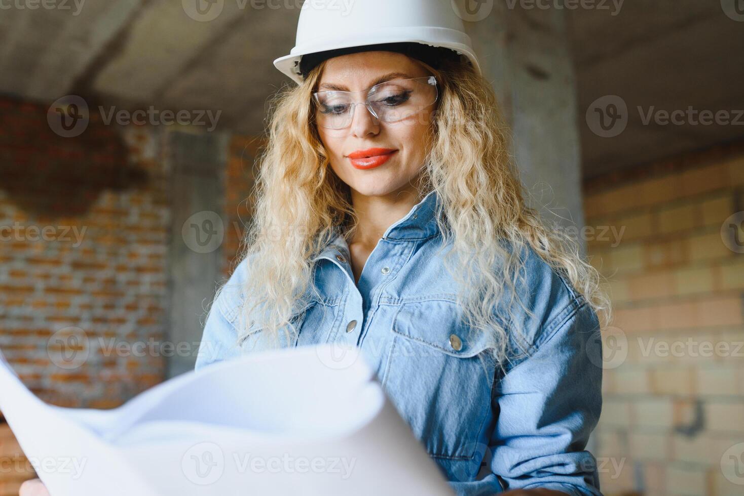 construção conceito. bonita fêmea construtor dentro macacão e capacete trabalhando em construção local. foto