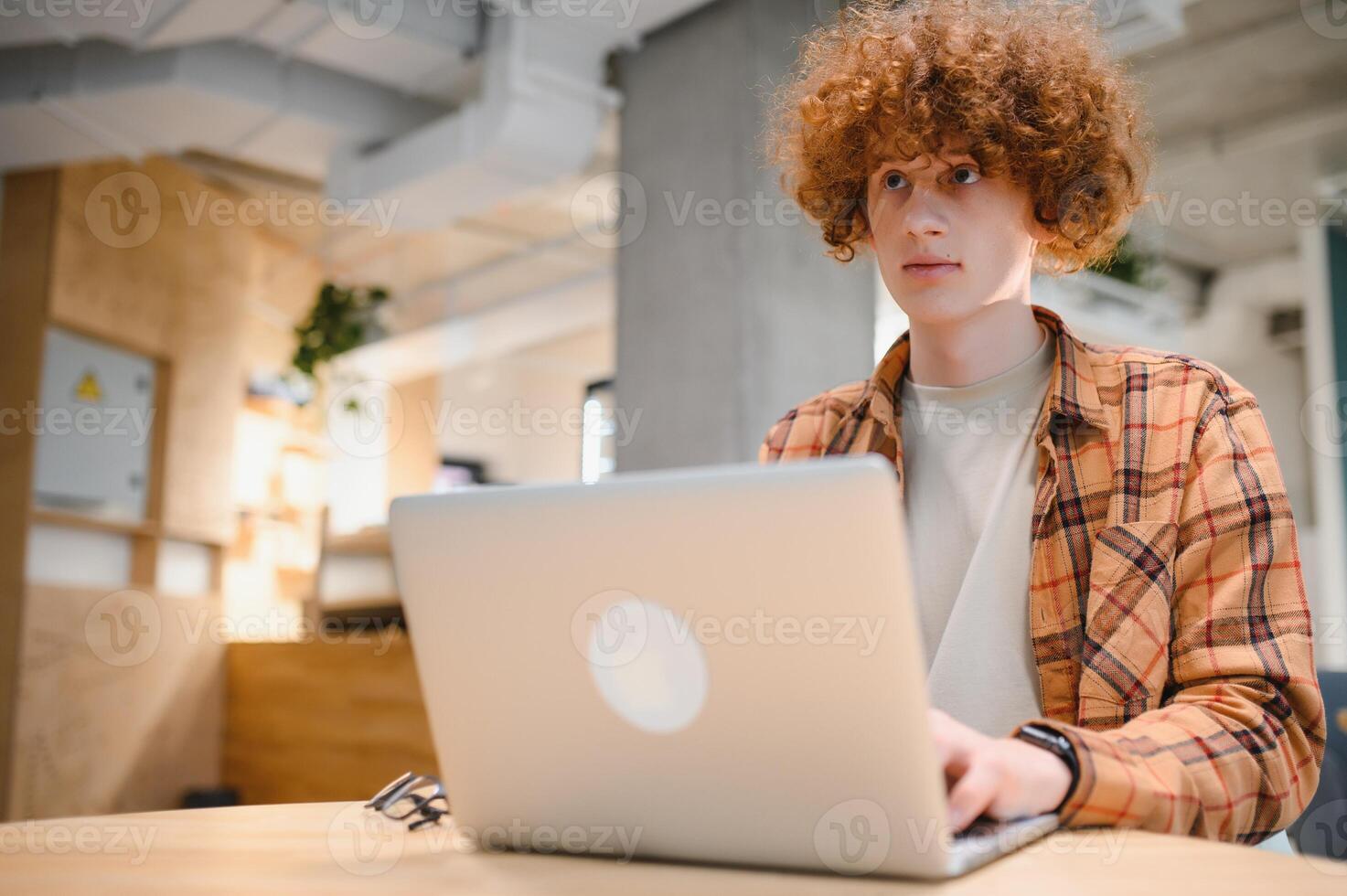 caucasiano hipster cara desfrutando distância trabalho dentro café comprar, masculino trabalhador autonomo dentro na moda óculos sentado dentro cantina com moderno computador portátil dispositivo foto