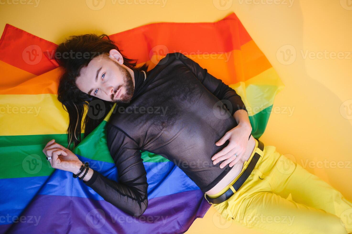 bonito jovem homem com orgulho movimento lgbt arco Iris bandeira em ombro contra branco fundo. homem com uma gay orgulho bandeira. foto