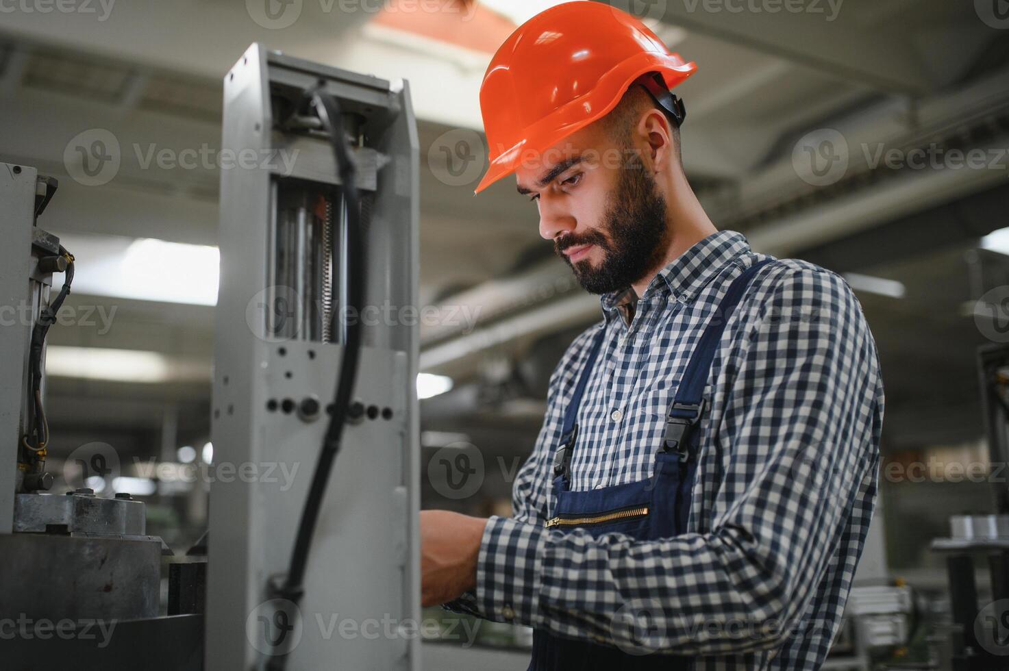 retrato do profissional pesado indústria engenheiro trabalhador vestindo segurança uniforme, Difícil chapéu sorridente. dentro a fundo desfocado ampla industrial fábrica. foto