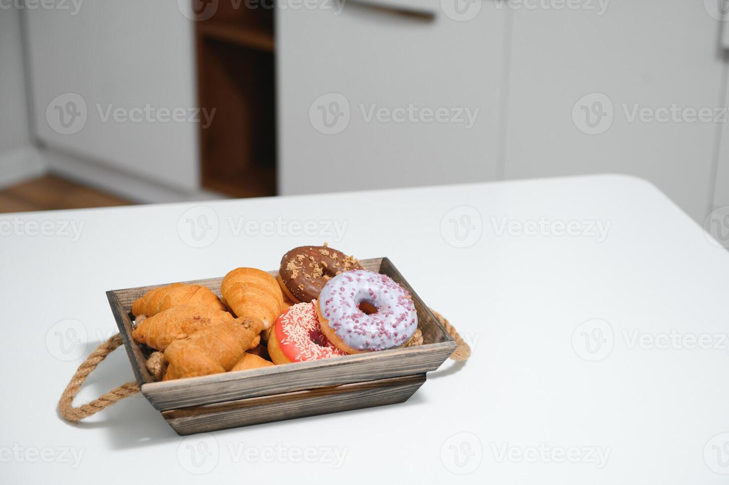 uma kraft caixa com pão produtos, rosquinhas, croissants dentro a cozinha foto