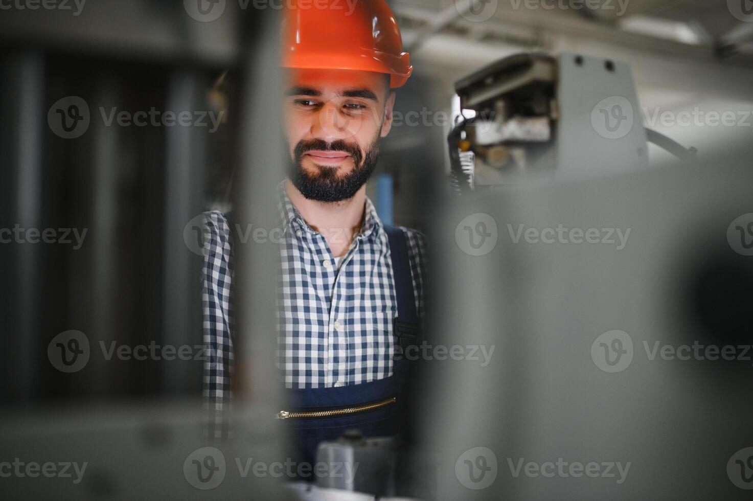 retrato do profissional pesado indústria engenheiro trabalhador vestindo segurança uniforme, Difícil chapéu sorridente. dentro a fundo desfocado ampla industrial fábrica. foto