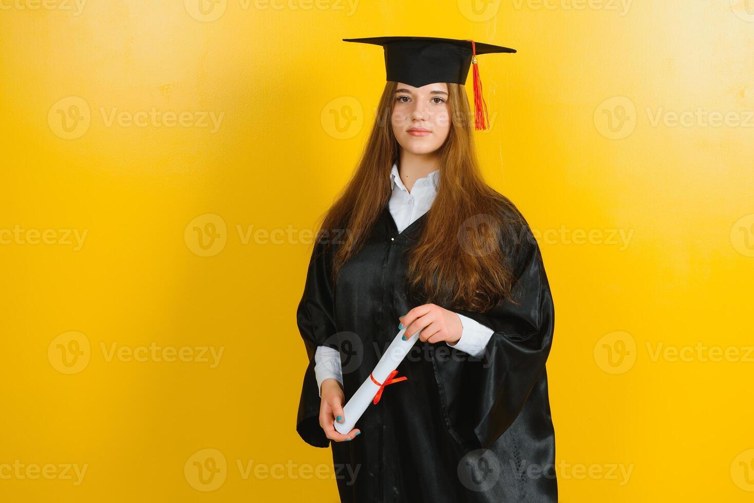 feliz atraente graduado dentro uma mestrado vestir, com uma diploma em uma amarelo fundo. conceito do a graduação cerimônia foto