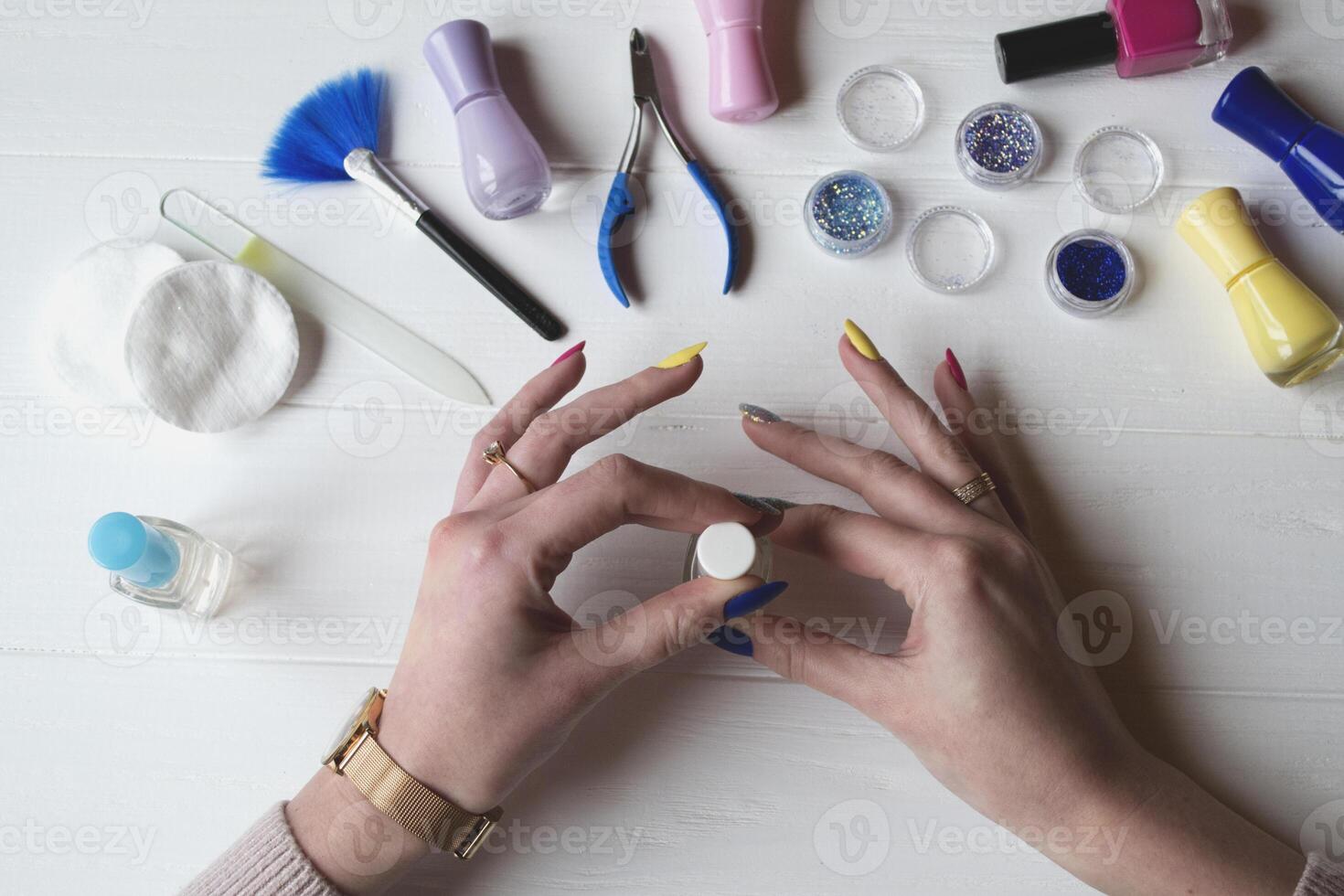 uma mulher pintura dela unhas. Ferramentas para manicure em uma branco de madeira mesa. foto