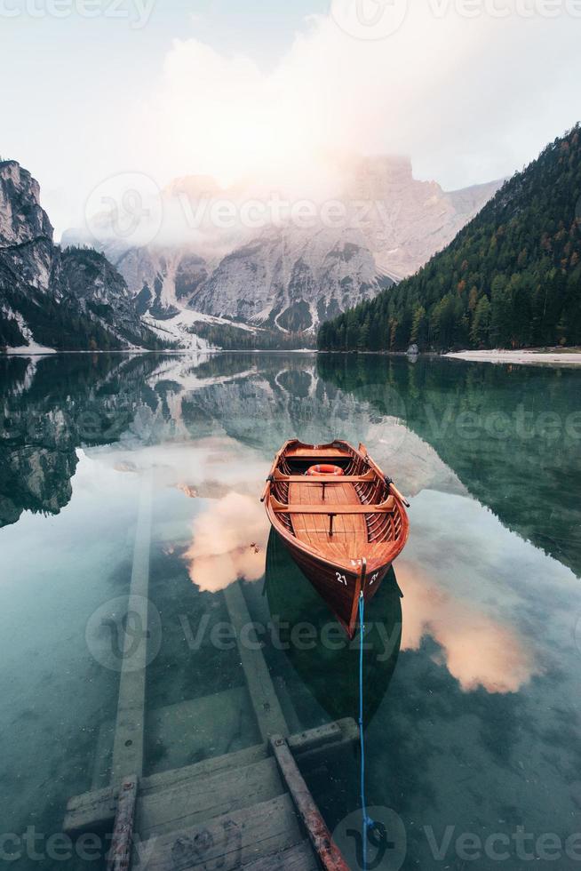 escadas que vão para a água. barco de madeira no lago de cristal com uma montanha majestosa atrás foto