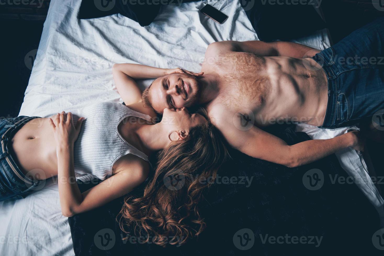 um retrato de um jovem casal feliz que relaxa em uma cama aconchegante foto