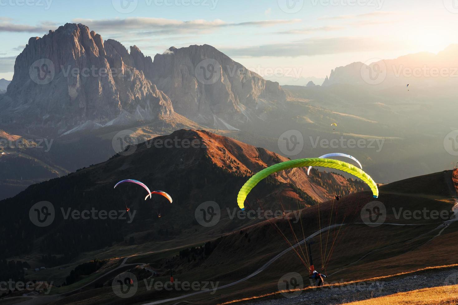 espetáculo de tirar o fôlego. muitos dos parapentes voando sobre as montanhas dolomitas seceda ao amanhecer foto