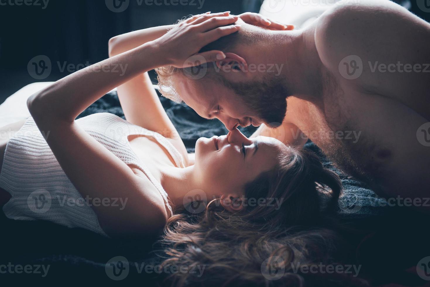 um retrato de um jovem casal feliz que relaxa em uma cama aconchegante foto
