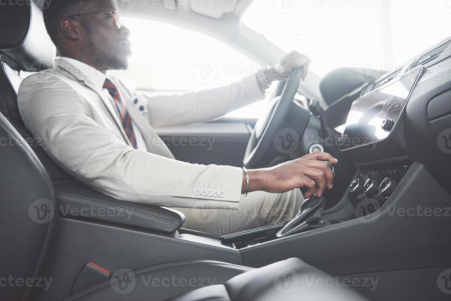 elegante empresário negro sentado ao volante de um carro de luxo. homem afro-americano rico foto