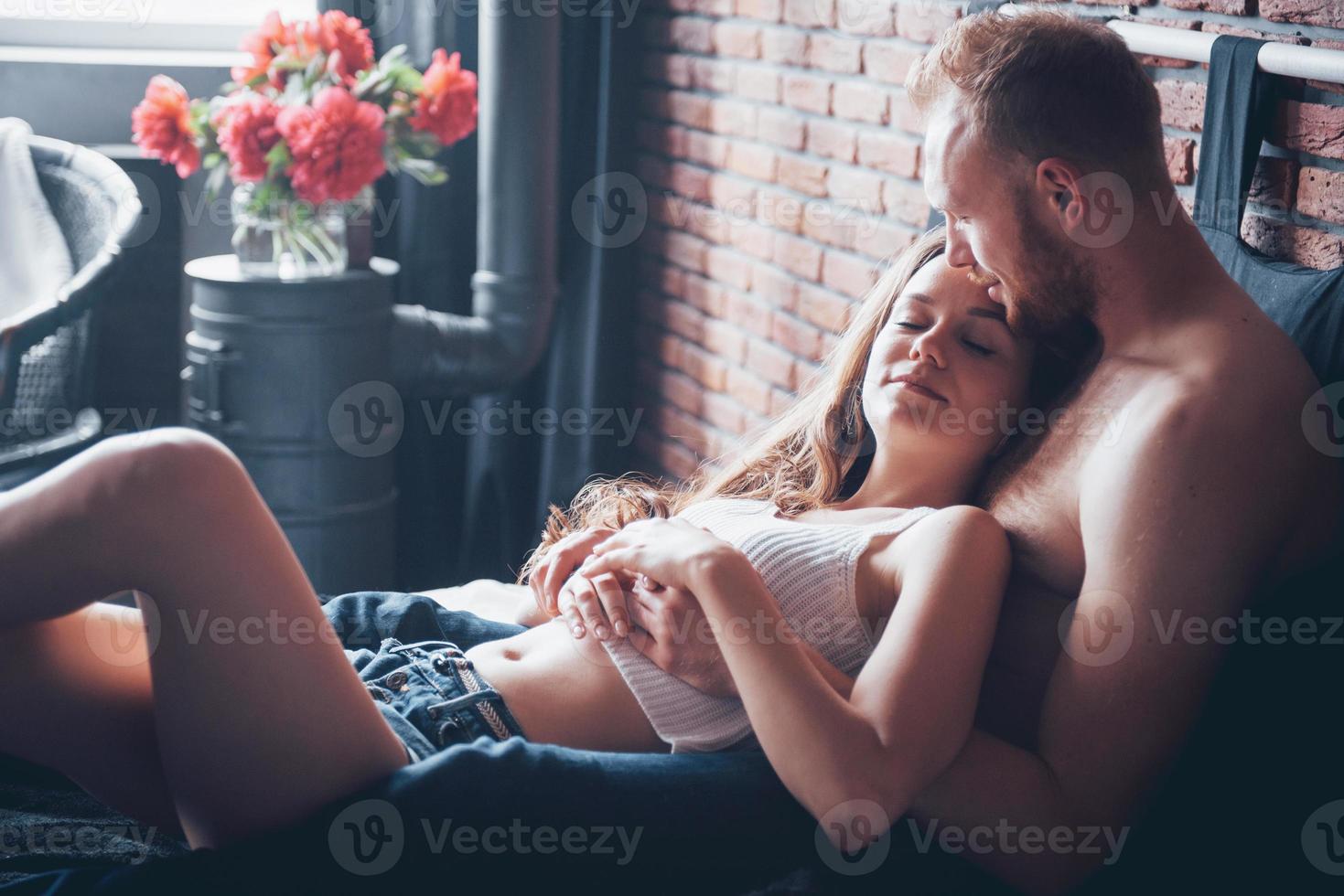 um retrato de um jovem casal feliz que relaxa em uma cama aconchegante foto