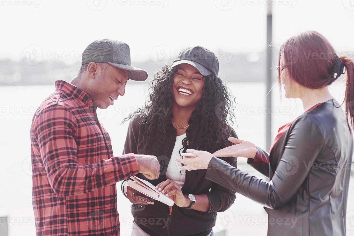 um grupo de jovens multinacionais com um livro, alunos que estudam ao ar livre foto