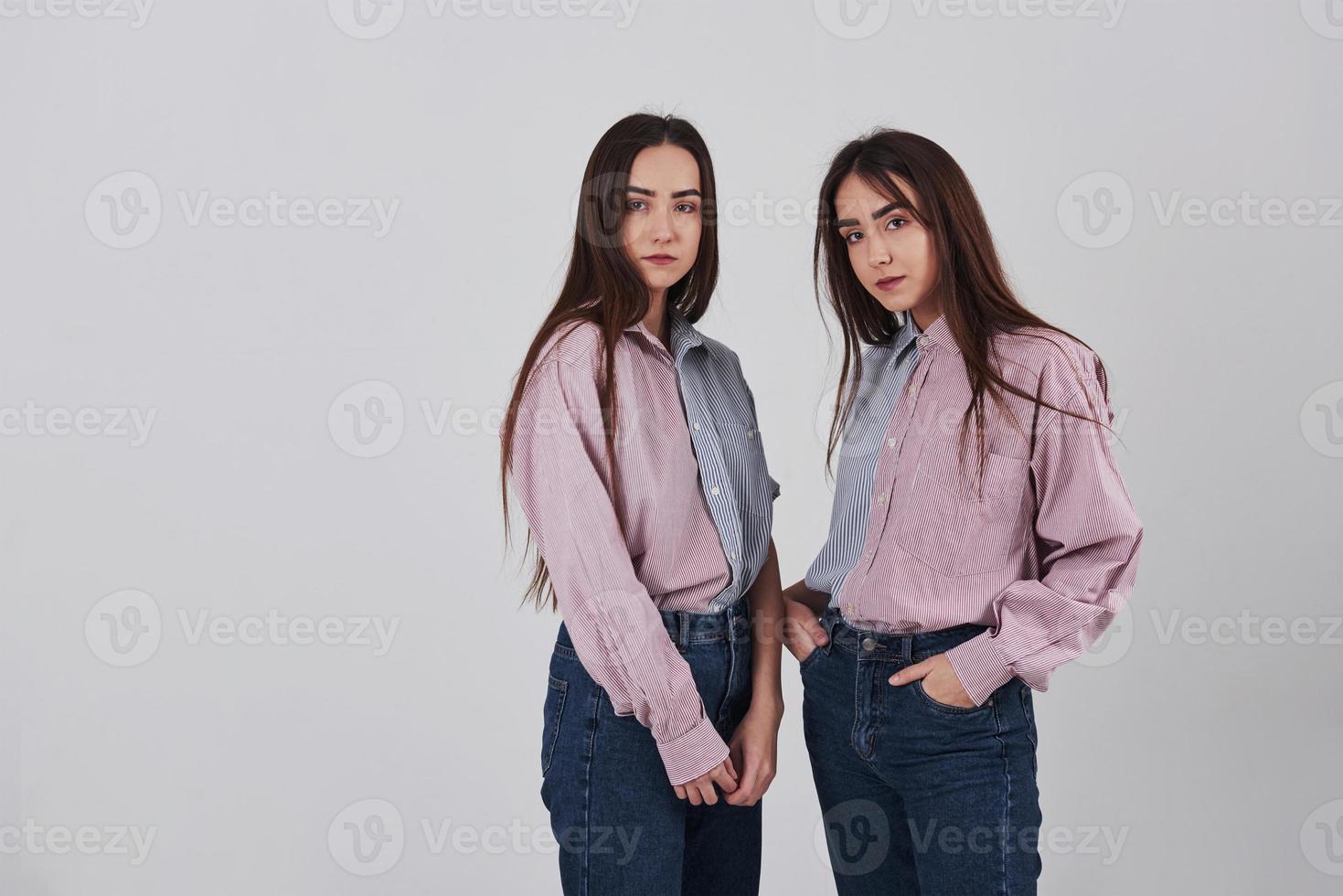 duas irmãs gêmeas em pé e posando no estúdio com fundo branco foto