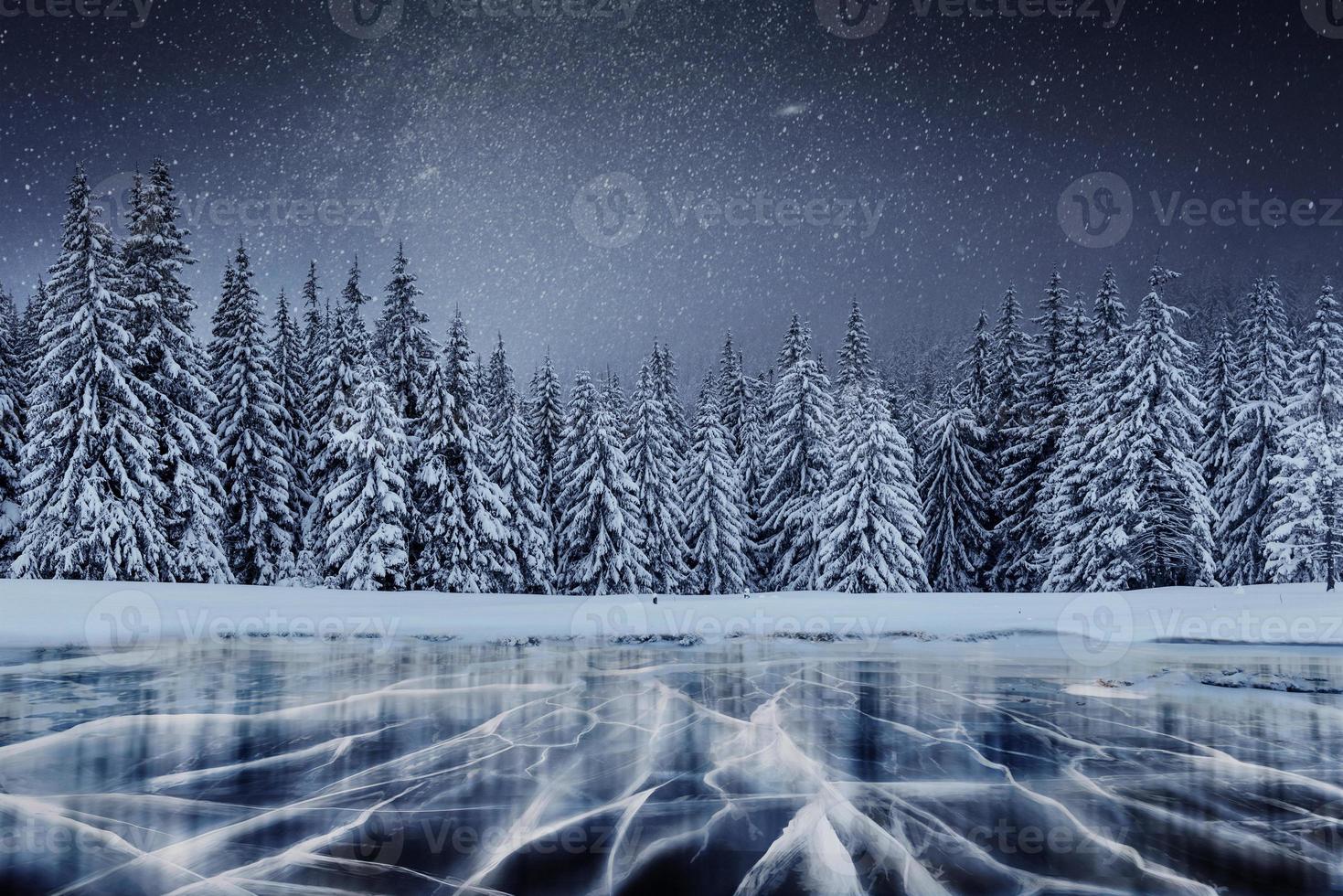 jornada de estrela de laticínios acima da floresta de inverno. rachaduras na superfície do gelo azul perto de colinas de pinheiros. lago congelado nas montanhas. cárpato ucrânia europa foto