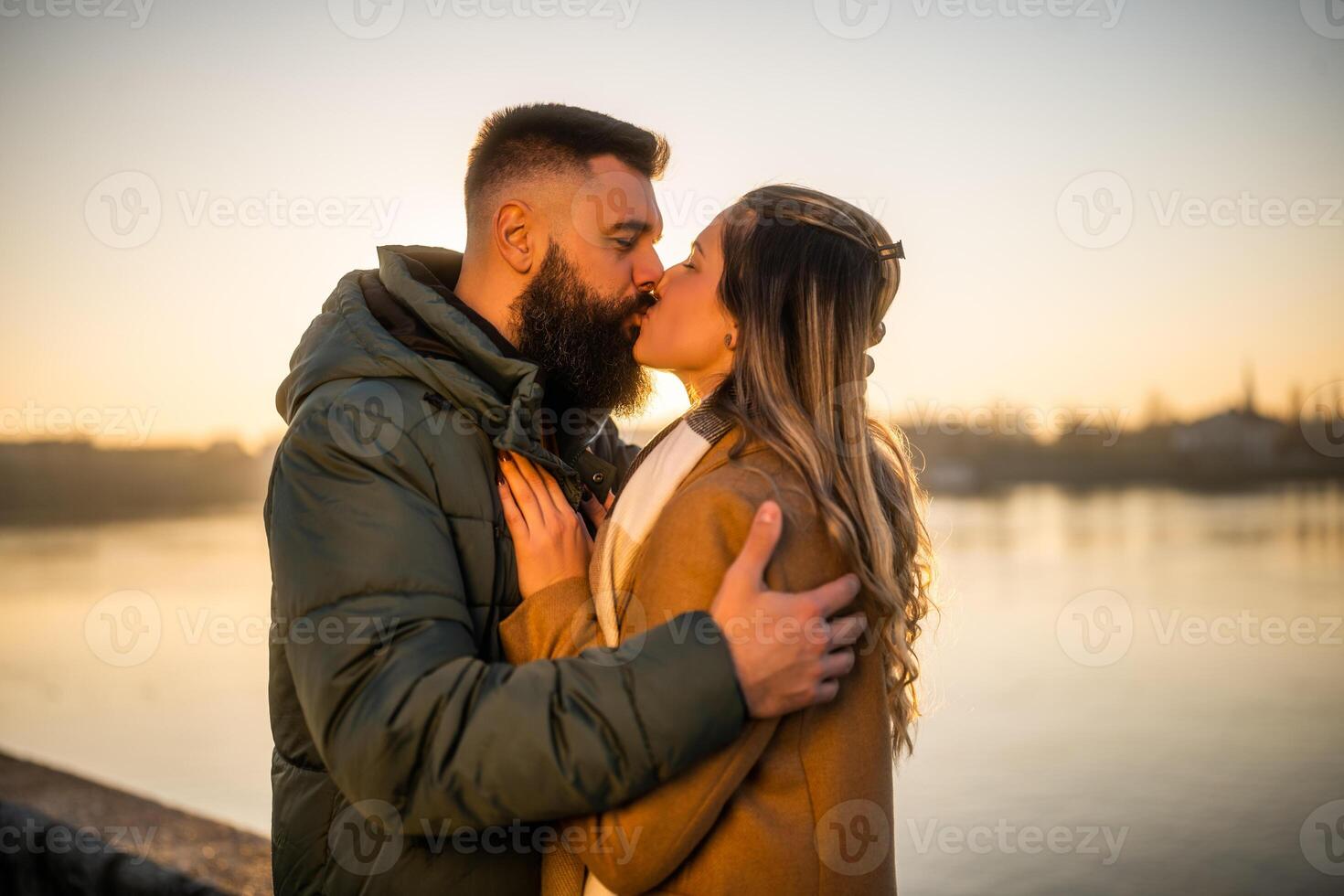 feliz casal se beijando e apreciar gastos Tempo juntos ao ar livre em uma pôr do sol. foto