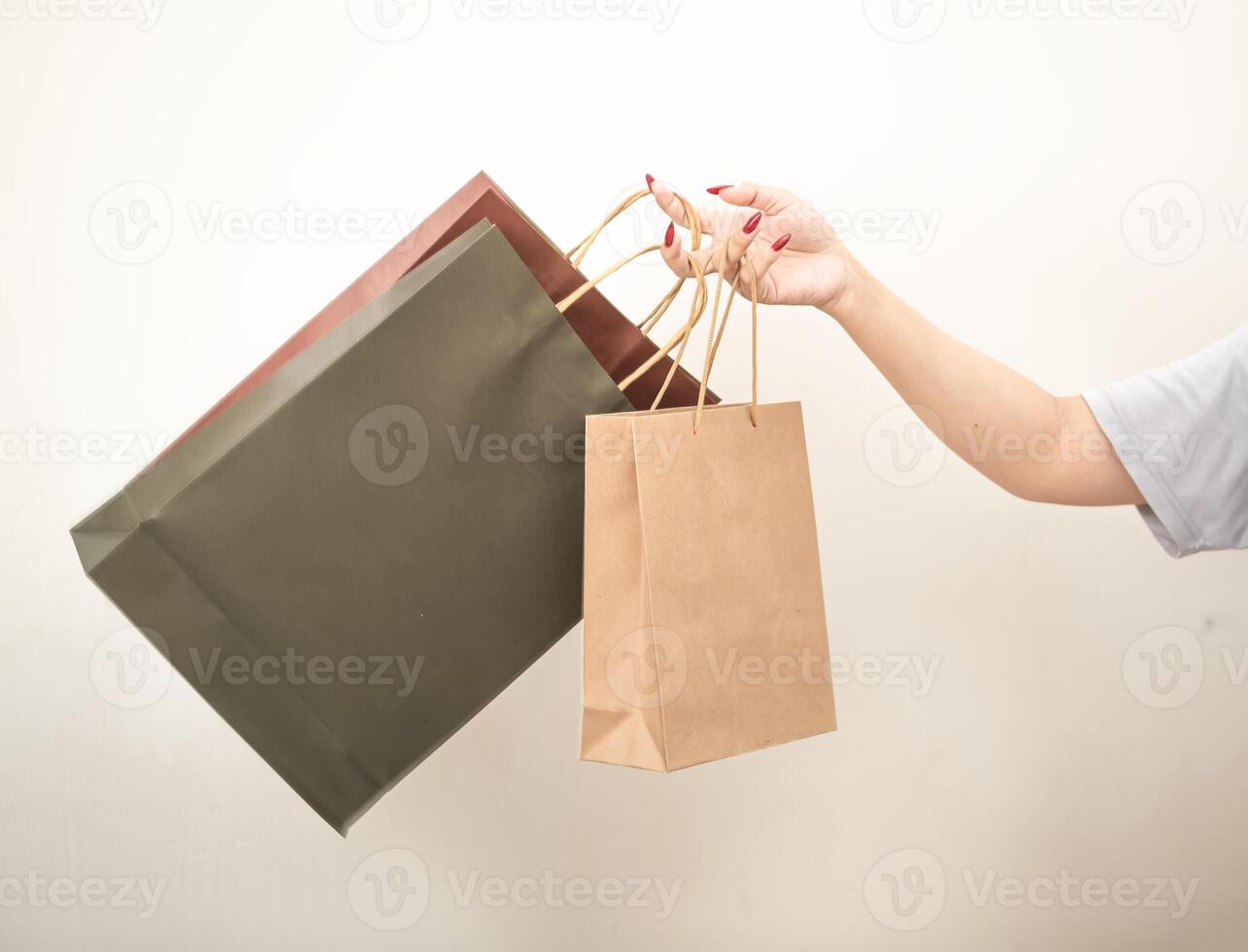 mão segurando uma compras papel saco contra uma branco isolado fundo foto