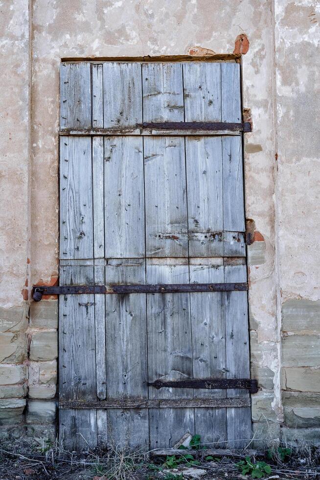 a velho de madeira porta é fechadas com parafusos. a Entrada para a construção do a antigo estrutura, uma cinzento de madeira tela de pintura fecha a Entrada para a casa. foto