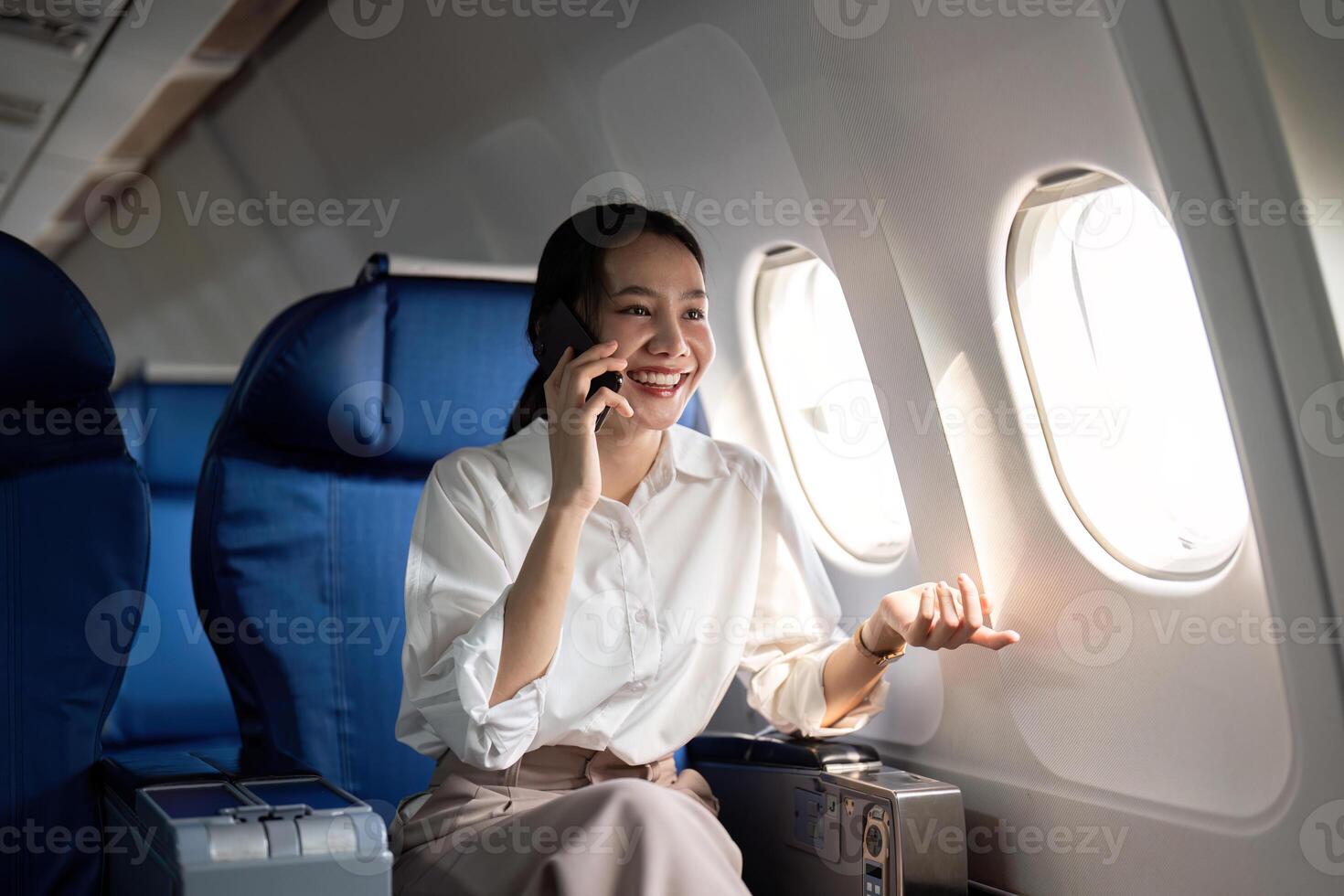 viajando e tecnologia. vôo às primeiro aula. jovem o negócio mulher passageiro usando Smartphone enquanto sentado dentro avião voar foto