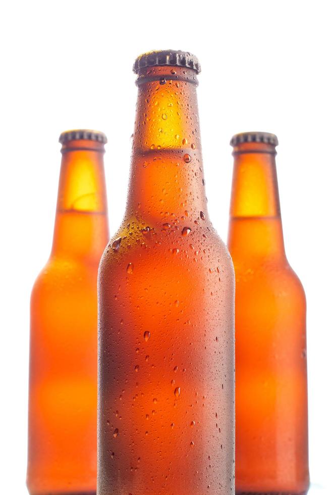 três garrafas de cerveja fresca em fundo branco foto