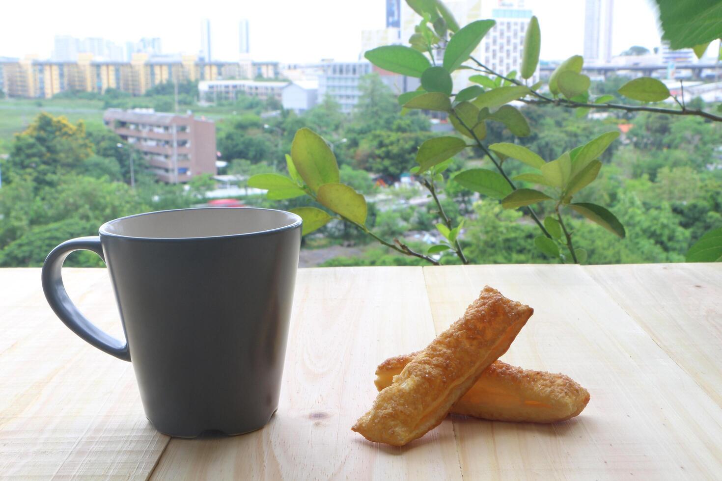 café copo e torta em de madeira mesa dentro a terraço. olhando Fora para a paisagens urbanas. foto