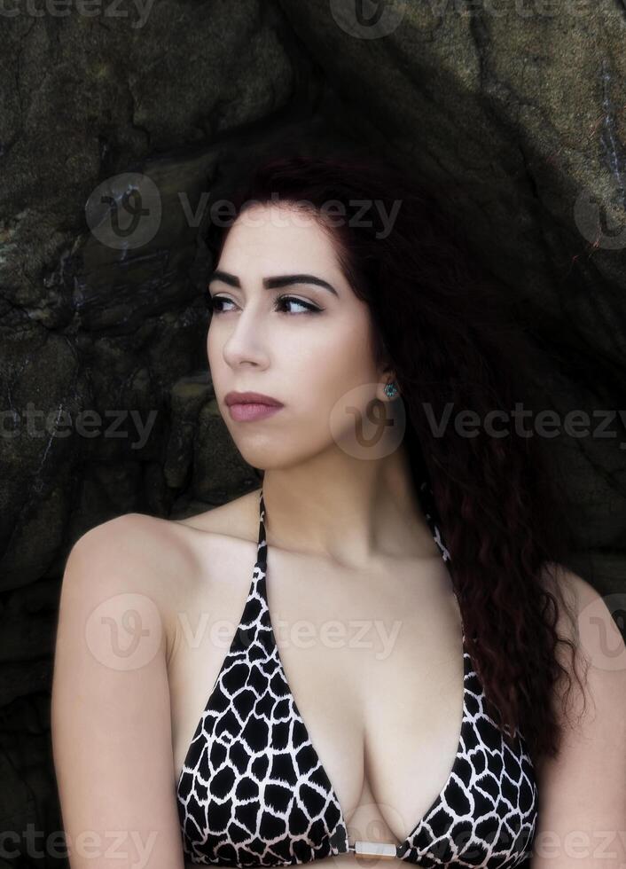 atraente hispânico mulher bikini topo contra pedras foto