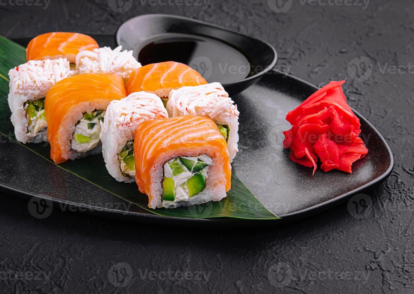 Sushi rolos com salmão e caranguejo em Preto prato foto