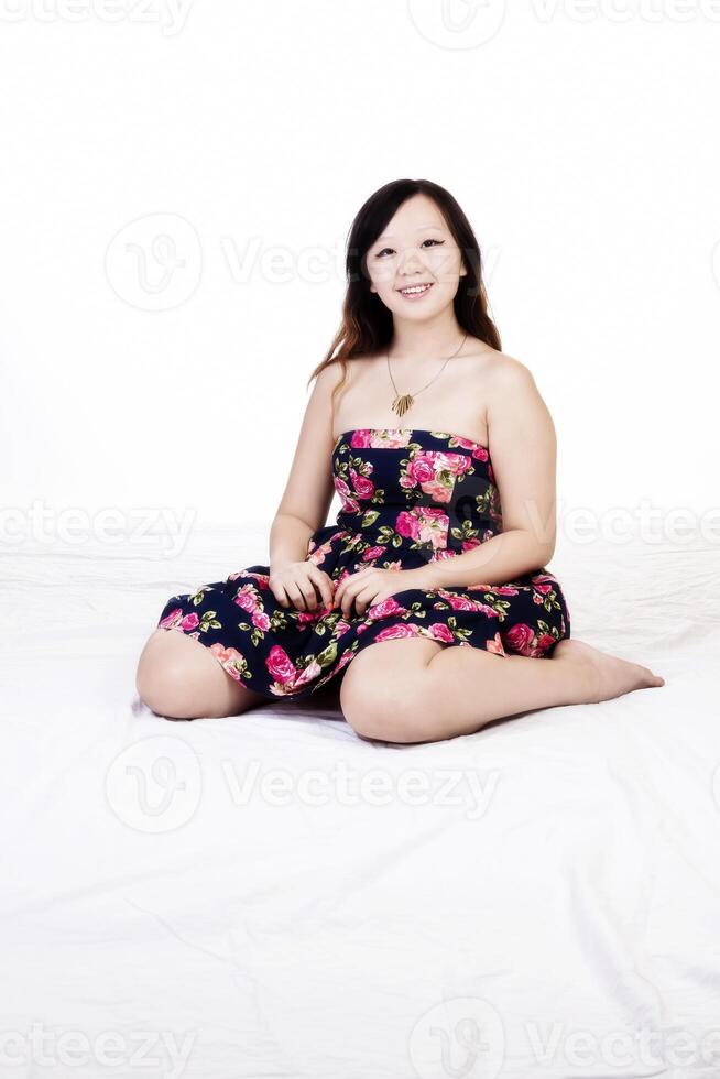 roliço chinês americano mulher sentado dentro floral vestir foto