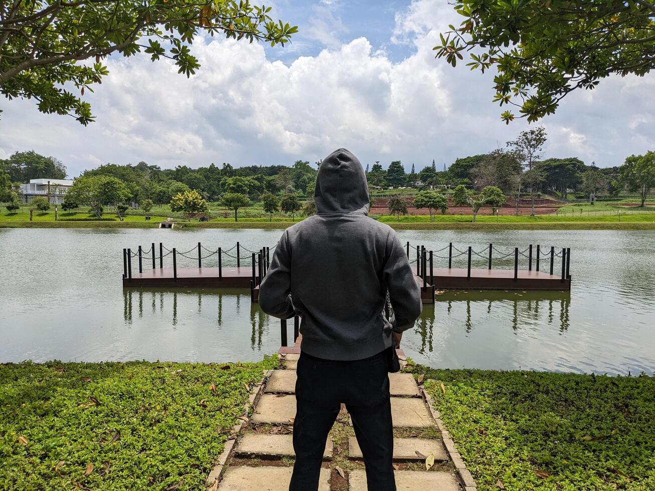 homem ficar de pé dentro frente do a caminho lago em baixa cidade. a foto é adequado para usar para aventura conteúdo meios de comunicação, natureza poster e floresta fundo.