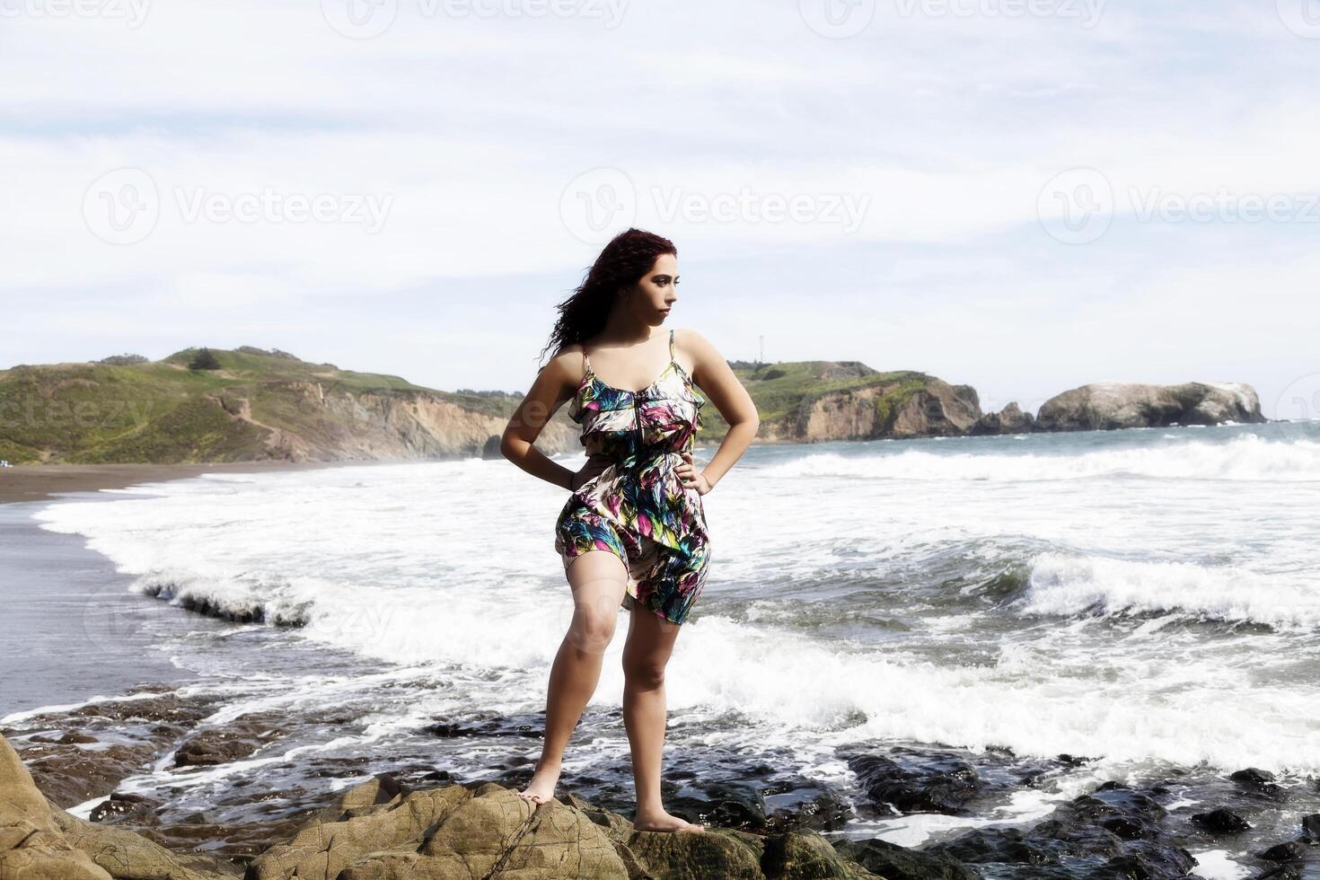 latina mulher em pé em pedras às de praia dentro vestir foto