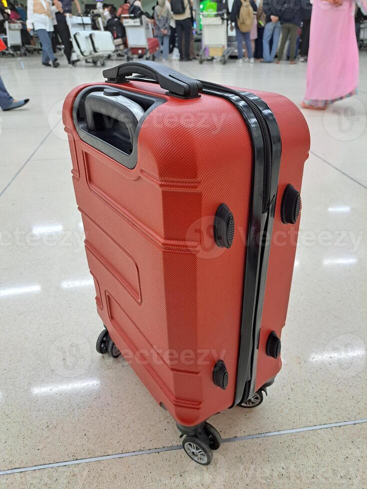 uma vermelho mala de viagem com Preto linhas em a zíper e rodas é muito adequado para grandes viagens ou viagem foto