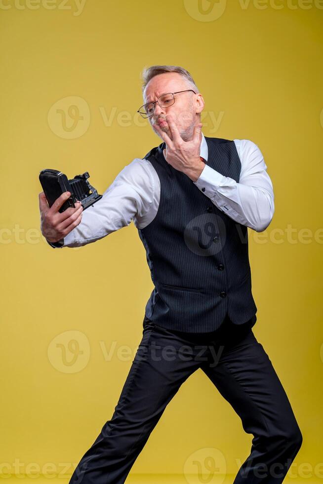 Senior homem olhando às Câmera enquanto levando boba face selfie acenando para a Câmera foto